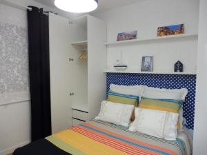 Schlafzimmer mit einem Bett mit bunter Bettwäsche und Kissen in der Unterkunft Herama Sea Guesthouse in Vila Nova de Gaia
