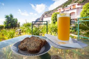 a plate of bread and a glass of orange juice at Cecília's House in Jardim do Mar