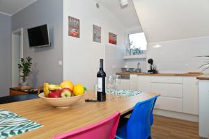 a table with a bowl of fruit and a bottle of wine at Old Town Apartments in Szczecin