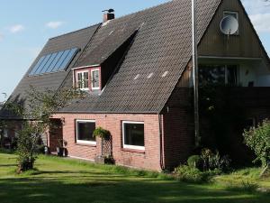 a red brick house with a solar roof at Süderdeich in Koldenbüttel +8 photos