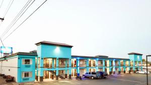 een rij blauwe gebouwen met auto's geparkeerd op een parkeerplaats bij Holiday Lodge - Salem,OR in Salem