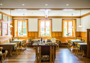 un comedor con mesas, sillas y ventanas en Land-gut-Hotel Landgasthof zur Rose, en Ehingen