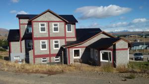 une grande maison assise sur le côté d'une route dans l'établissement Edelweiss Hostel, à El Calafate