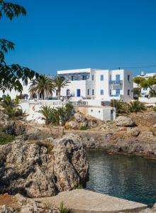 a building on a beach with a body of water at Avlemonas Bay Sea Houses. in Avlemonas