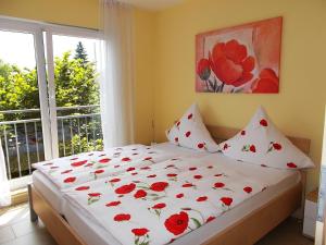 a bedroom with a bed with red flowers on it at Ferienwohnungen Uhlemann - nur 15 Minuten bis in die Altstadt in Dresden