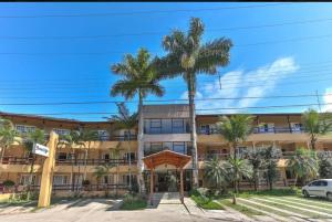 un grand bâtiment avec des palmiers devant lui dans l'établissement Flat Amarilis und 110 Riviera de Sao Lourenco SP, à Riviera de São Lourenço