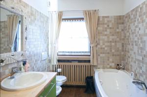 ein Badezimmer mit einer Badewanne, einem Waschbecken und einem WC in der Unterkunft Maso Gretel in Tesero