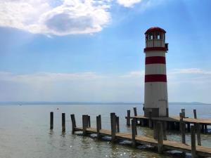 een rode en witte vuurtoren op een dok in het water bij Paradies Für Zwei in Frauenkirchen