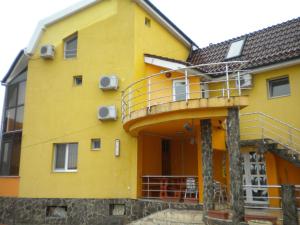 a yellow building with a balcony on it at Pensiunea Carmena in Baile Felix