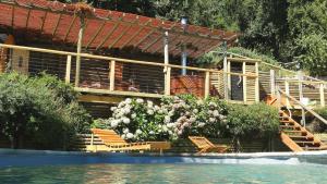 a house with chairs and flowers next to a swimming pool at Lodge Colbún in Colbún Alto