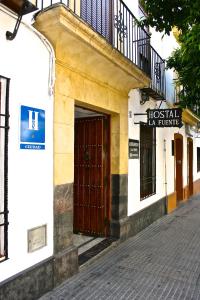 a building with a wooden door and a balcony at Hostal la Fuente in Córdoba