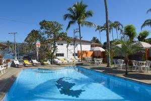 a large blue swimming pool with chairs and palm trees at Recanto das Carpas in Ilhabela
