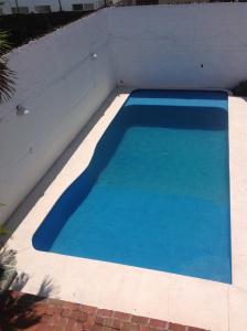 a blue swimming pool next to a white wall at Casa Bocoyna in Acapulco