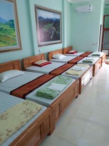 a row of four beds in a room at Yen Minh Hotel Thien An in Na Thôn