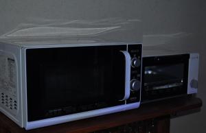 a microwave sitting on top of a wooden shelf at Spr Guesthouse in Shirahama