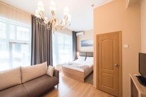 a bedroom with a bed and a couch and a chandelier at Teplo Hotel in Vladivostok