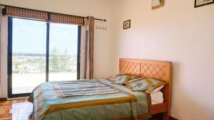 a bedroom with a bed and a large window at Palmyre Residence 7 & 8 LICENSED BY TOURISM AUTHORITY 10071 in Flic-en-Flac