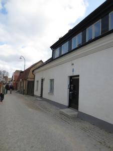 uma rua com um prédio branco e pessoas andando pela rua em Visby Innerstad Lägenheter & Rum em Visby