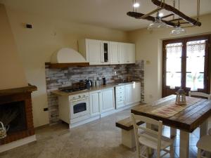 cocina con armarios blancos y mesa de madera en appartamento Podere i Renai, en Santa Maria a Monte