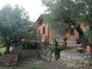 una casa antigua con una pared de piedra y árboles en Villetta dei tramonti, en San Feliciano