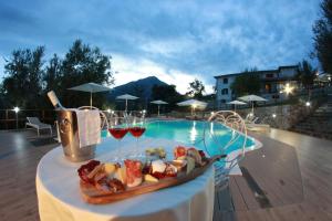 een dienblad met eten en wijn op een tafel naast een zwembad bij Tenuta Terre di Bosco Oasi di Relax nel Cilento in San Giovanni a Piro