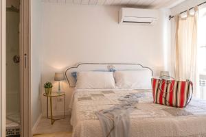a white bedroom with a bed with a striped bag on it at Casa Sferisterio Macerata in Macerata