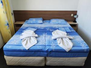 a bed with blue and white sheets and towels on it at Villa Maris in Obzor