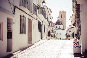 an alley with white buildings and a church at Gran H La Marina in Altea