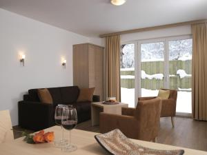 sala de estar con sofá y mesa con copa de vino en Apart Resort Rabl, en Westendorf