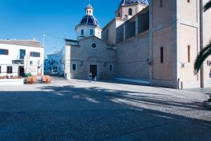 a person standing in front of a building with a church at Gran H La Marina in Altea