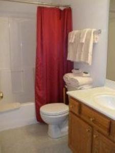a bathroom with a toilet and a red shower curtain at Eastside Suites in Lynchburg