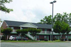 a large red brick building with cars parked in front of it at Eastside Suites in Lynchburg
