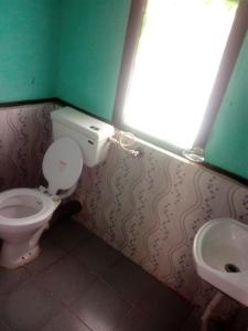 a bathroom with a toilet and a sink at Vamoose Green Valley Village Resort in Pedong
