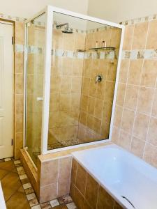 a bathroom with a shower and a bath tub at Cosy Private Cottage in Port Elizabeth