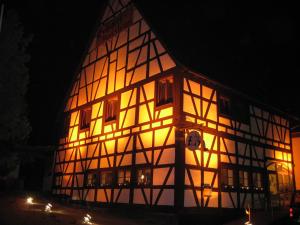 Un grand bâtiment est éclairé la nuit. dans l'établissement Landhotel im Hexenwinkel, à Wiernsheim