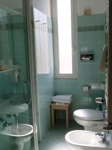 a green bathroom with a toilet and a sink at Hotel Savoy in Varazze