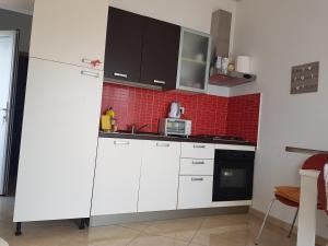 a kitchen with white cabinets and a red tile wall at Blue sea blue sky in Lovište +14 photos