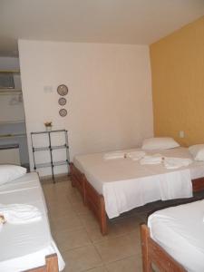 um quarto com três camas e um relógio na parede em Hotel Pousada Castanheiras do Village em Porto Seguro