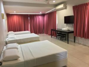 um quarto com 3 camas, uma secretária e uma cortina vermelha em Meng Meng GuestHouse em Kuantan
