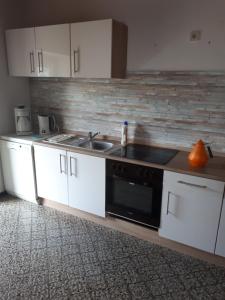 a kitchen with white cabinets and a sink and a stove at Ferienwohnung Frank in Merzalben