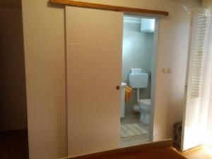 a door to a bathroom with a toilet in a room at Apartments & Rooms Brna in Rab