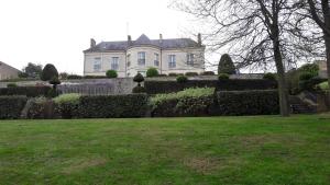 una grande casa con una siepe di fronte a un cortile di Suite Sainte Anne a Beaumont-sur-Sarthe