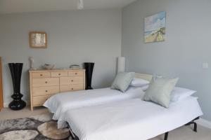 ウエストワード・ホーにあるSeafront House 3 - Golden Bay Holiday Villageのベッドルーム(ドレッサー付)の白いベッド2台