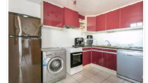 een keuken met rode kasten en een wasmachine bij F3 NARBONE-PLAGE AVEC SOLARIUM 250M DE LA MER VUE MER ET CLAPE in Narbonne-Plage