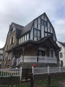 een groot huis met een wit hek ervoor bij villa Suècia in De Panne