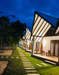 a row of white buildings with a grass yard at Riva del Sole Guest House in Arugam Bay