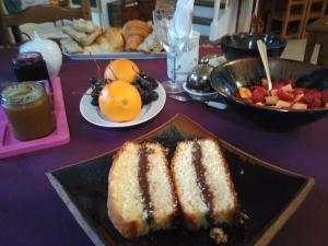 a table with a plate of cake and a bowl of fruit at La chambre du harpiste in Saint-Mars-la-Jaille