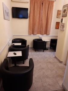 une salle d'attente avec des chaises noires et une télévision dans l'établissement Hotel Ottavia, à Rimini