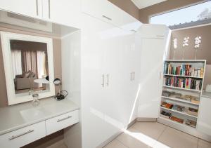 uma casa de banho branca com um lavatório e uma estante de livros em RnB's Studio Apartment em Windhoek