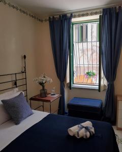 a bedroom with a bed and a window with blue curtains at Le Petit Bouganville in Salerno